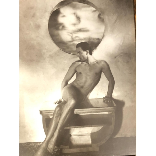 2076 - A framed sepia print of a nude man sitting on a table, 49.5cm x 69cm.