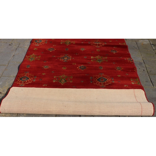 3173 - A modern rug on red ground with green, blue and cream pattern, 148.5cm wide, 235cm long. (This item ... 