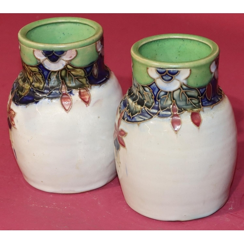 100 - A pair of Royal Doulton glazed earthenware round bulbous thin necked vases on white ground with mult... 