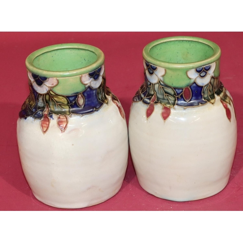 100 - A pair of Royal Doulton glazed earthenware round bulbous thin necked vases on white ground with mult... 