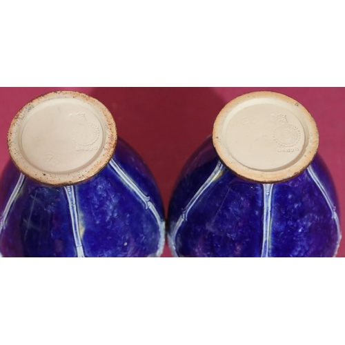 101 - A pair of Royal Doulton glazed earthenware round bulbous thin necked trumpet shaped vases on blue an... 