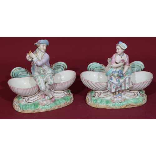 102 - A pair of 19th/20th Century Continental porcelain salts in the form of figures seated upon shells, 1... 