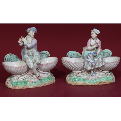 102 - A pair of 19th/20th Century Continental porcelain salts in the form of figures seated upon shells, 1... 