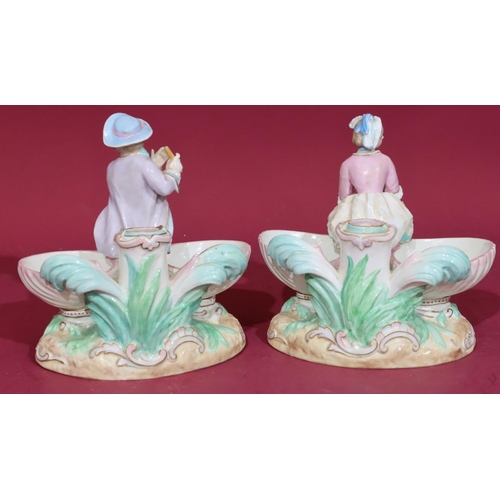 102 - A pair of 19th/20th Century Continental porcelain salts in the form of figures seated upon shells, 1... 