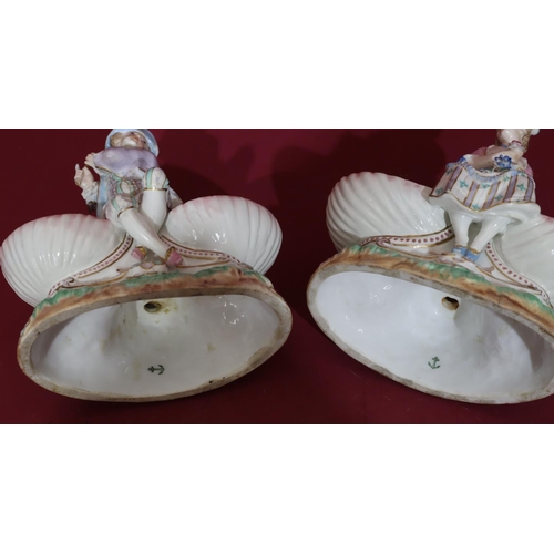 102 - A pair of 19th/20th Century Continental porcelain salts in the form of figures seated upon shells, 1... 