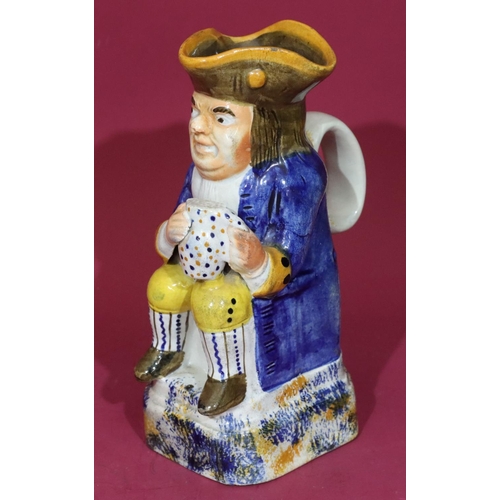 115 - A Staffordshire small toby jug in the form of a seated gentleman holding a jug in blue jacket, 18.5c... 