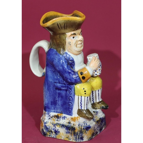 115 - A Staffordshire small toby jug in the form of a seated gentleman holding a jug in blue jacket, 18.5c... 