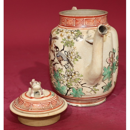 63 - An Oriental glazed earthenware teapot on white and red ground with bird, floral, leaf and key patter... 