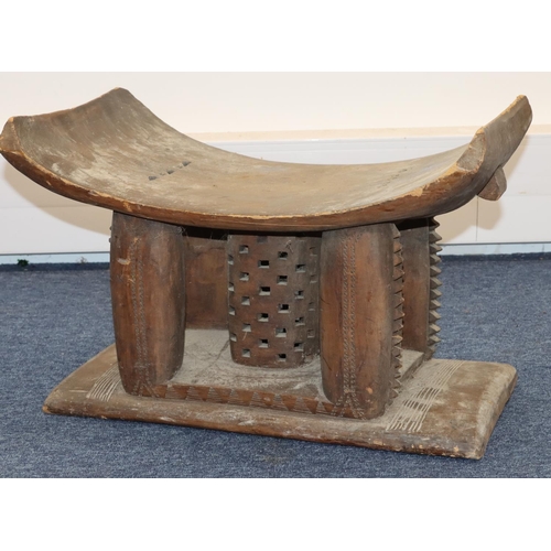 705 - An Ashanti stool with curved top, carved supports, on rectangular base, 56cm wide, 34cm deep, 37cm h... 