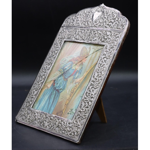 269 - A Continental silver coloured metal freestanding photograph frame with allover embossed floral, leaf... 