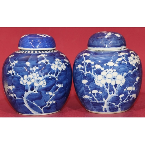 104 - A pair of Oriental round bulbous lidded ginger jars on blue and white ground with branch and blossom... 