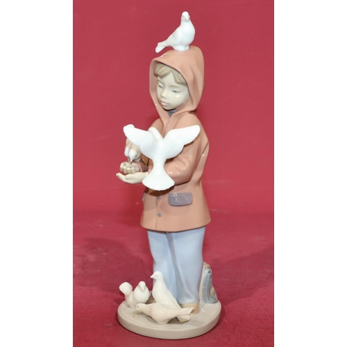 132 - A Lladro figure of a young boy holding doves, 24cm high.