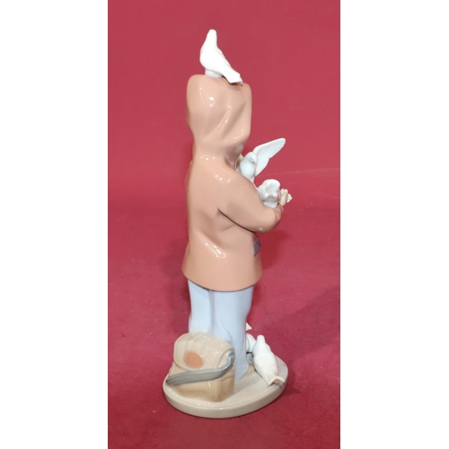 132 - A Lladro figure of a young boy holding doves, 24cm high.