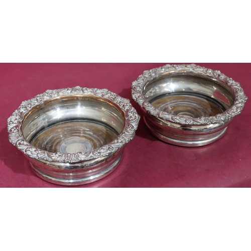 219 - A pair of silver plated round bulbous shaped wine coasters with raised shell, leaf and scroll rims a... 