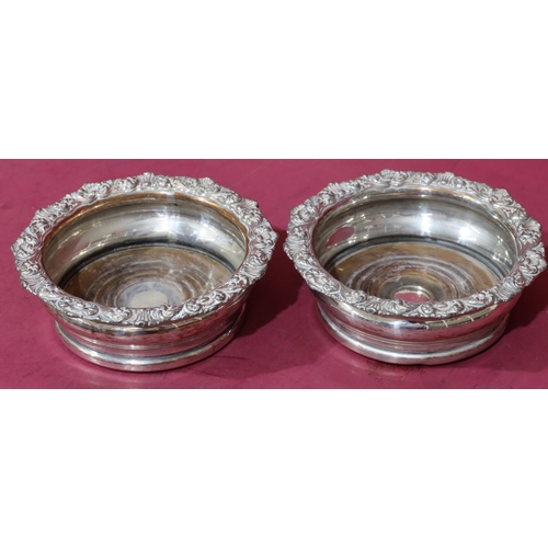 219 - A pair of silver plated round bulbous shaped wine coasters with raised shell, leaf and scroll rims a... 