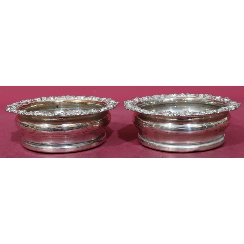 219 - A pair of silver plated round bulbous shaped wine coasters with raised shell, leaf and scroll rims a... 