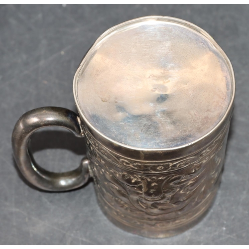 242 - A silver coloured metal christening mug with allover embossed leaf and scroll decoration, 7.2cm high... 