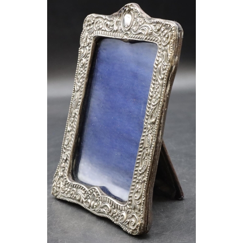 259 - A silver mounted freestanding photograph frame with embossed floral, leaf and scroll rim (slight dam... 