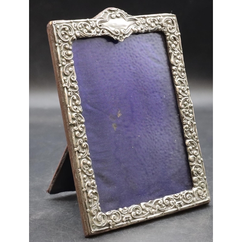 260 - A silver mounted freestanding photograph frame with allover embossed floral, leaf and scroll decorat... 