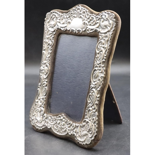 265 - A London silver mounted freestanding photograph frame with embossed bird, shell and scroll decoratio... 