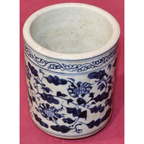 43 - An Oriental cylindrical blue and white brush pot with floral and leaf decoration, 12.5cm high