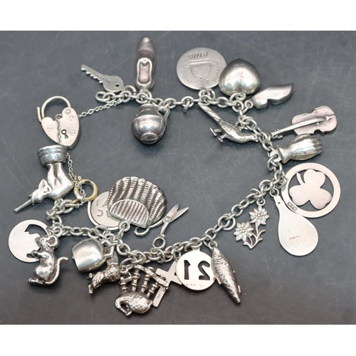 540 - A silver charm bracelet mounted with padlock clasp and 23 charms, 43 grams