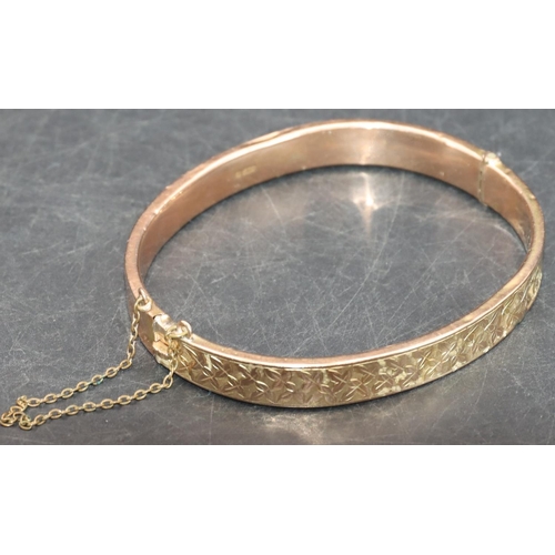 542 - A 9ct gold hinged bangle with engraved leaf decoration (some dents), 8.5 grams