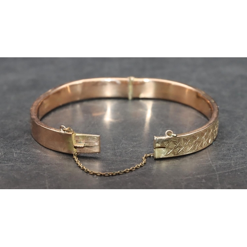 542 - A 9ct gold hinged bangle with engraved leaf decoration (some dents), 8.5 grams