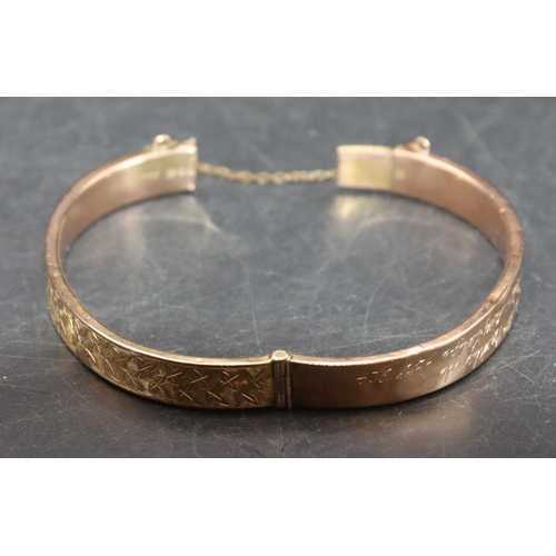 542 - A 9ct gold hinged bangle with engraved leaf decoration (some dents), 8.5 grams