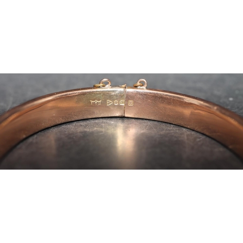 542 - A 9ct gold hinged bangle with engraved leaf decoration (some dents), 8.5 grams