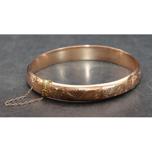 543 - A 9ct gold hinged bangle with part engraved decoration, 8.9 grams