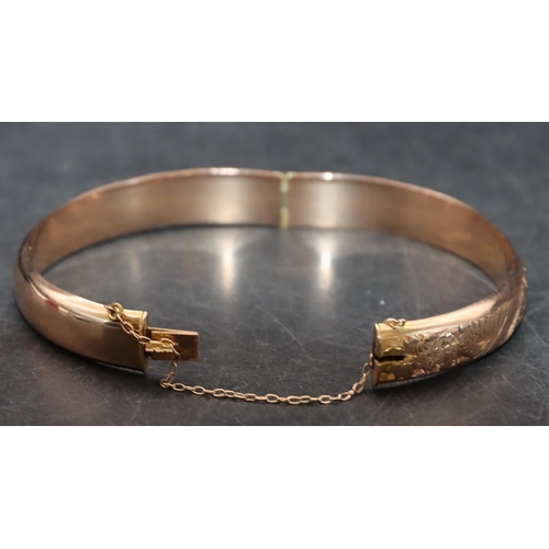 543 - A 9ct gold hinged bangle with part engraved decoration, 8.9 grams