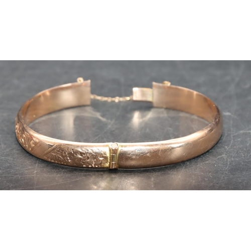 543 - A 9ct gold hinged bangle with part engraved decoration, 8.9 grams