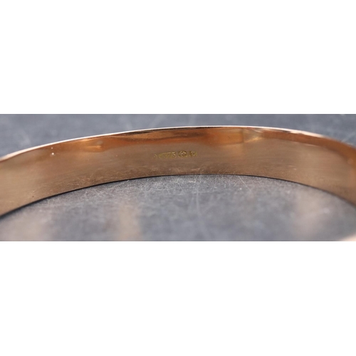 543 - A 9ct gold hinged bangle with part engraved decoration, 8.9 grams