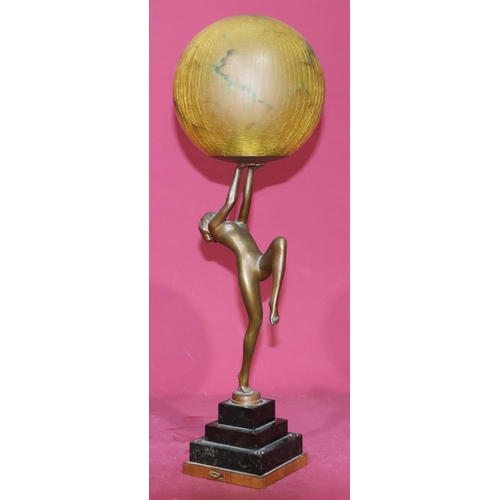 627 - An Art Deco bronze table lamp in the form of a standing female nude holding a circular shade on a sq... 