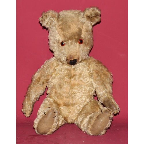 652 - An antique teddy bear with glass eyes (some wear and arms in need of re-padding), 45cm high