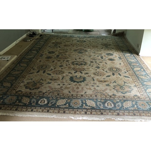 4250 - A large wool rug on cream ground with multi-coloured pattern, tassels to end (some scattered spots a... 