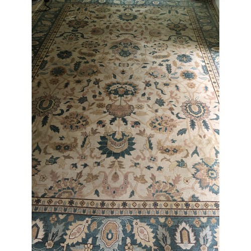 4250 - A large wool rug on cream ground with multi-coloured pattern, tassels to end (some scattered spots a... 