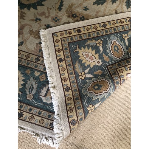 4250 - A large wool rug on cream ground with multi-coloured pattern, tassels to end (some scattered spots a... 