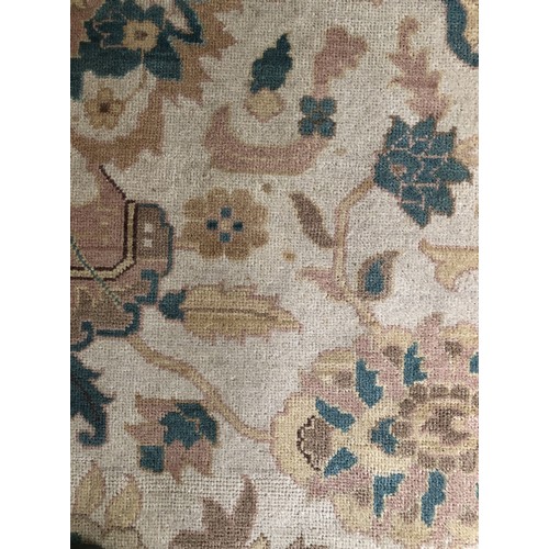 4250 - A large wool rug on cream ground with multi-coloured pattern, tassels to end (some scattered spots a... 