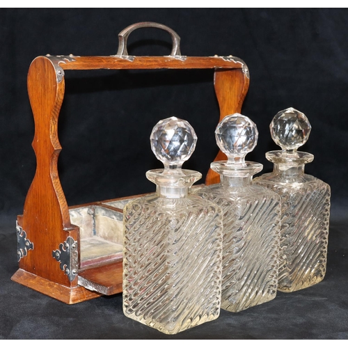 728 - An oak 3-bottled tantalus with silver plated handle and mounts, set with 3 cut glass square decanter... 