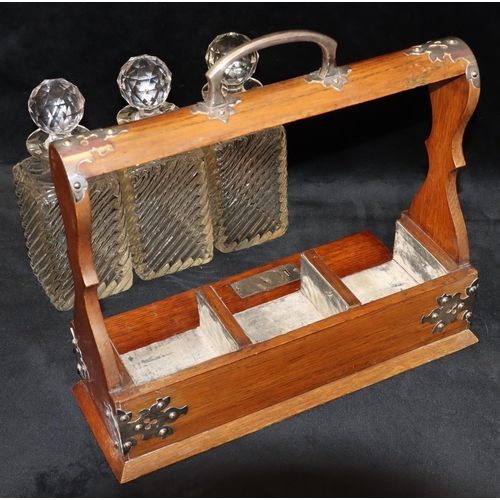 728 - An oak 3-bottled tantalus with silver plated handle and mounts, set with 3 cut glass square decanter... 