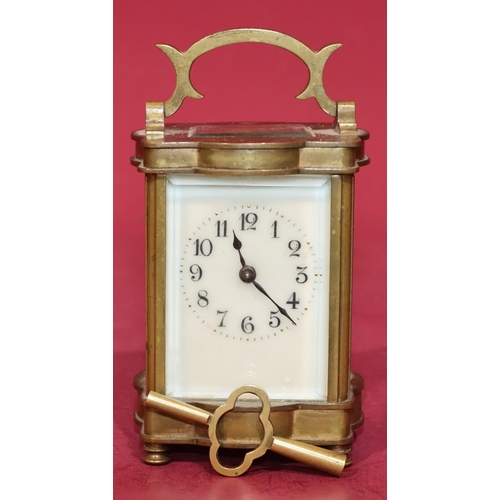 744 - A miniature brass carriage clock with cream enamel dial and Arabic numerals, swing overhead handle o... 