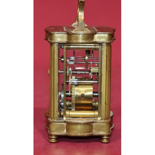 744 - A miniature brass carriage clock with cream enamel dial and Arabic numerals, swing overhead handle o... 