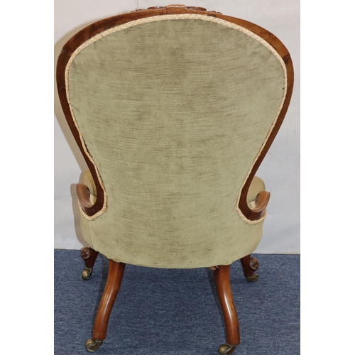 768 - A Victorian walnut spoon back nursing chair with green velvet overstuffed seat and button back, on c... 