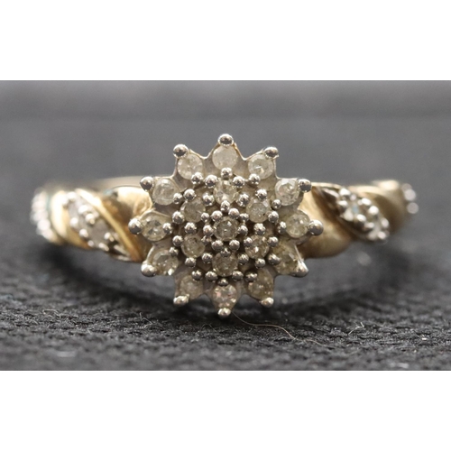 589 - A 9ct gold ladies' circular cluster ring set with small diamond chips with further diamond chips to ... 