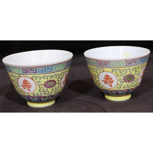 132 - A pair of Oriental tea bowls on yellow ground with coloured key pattern, scroll and floral decoratio... 