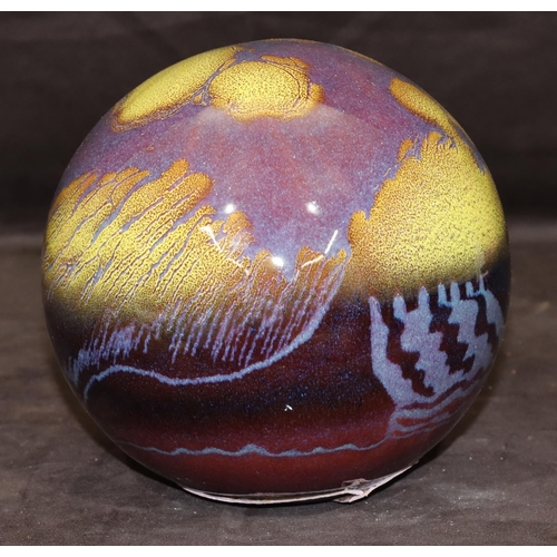 33 - A glazed earthenware globe with yellow and purple decoration, 19cm high