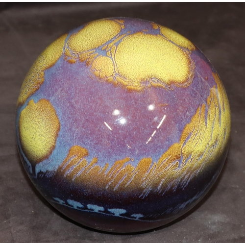 33 - A glazed earthenware globe with yellow and purple decoration, 19cm high