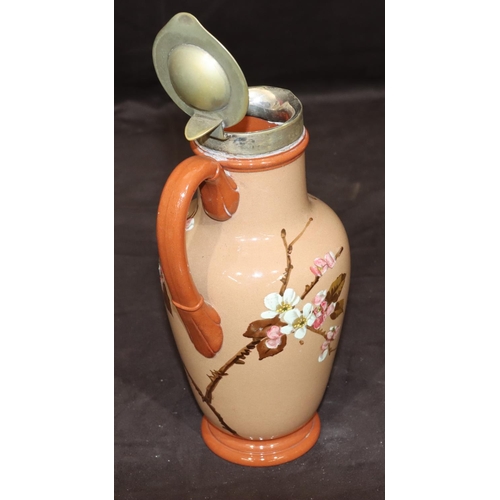 34 - A Victorian glazed earthenware round bulbous jug with silver plated neck and hinged lid on brown gro... 